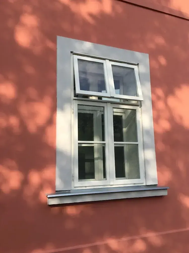 Bílé dřevěné okno v červené fasádě