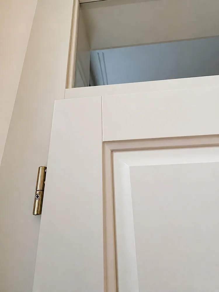 Bílý dřevěný rám dveří s bronzovým pantem