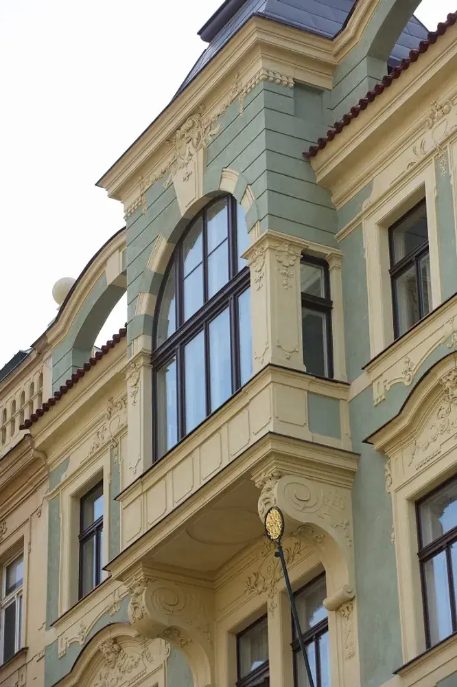 Dřevěná okna na historické budově s bohatou štukovou výzdobou