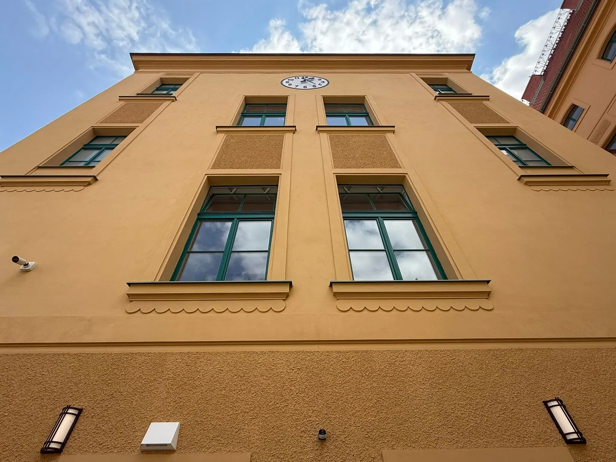 Zelená dřevěná okna na žluté fasádě bytového domu