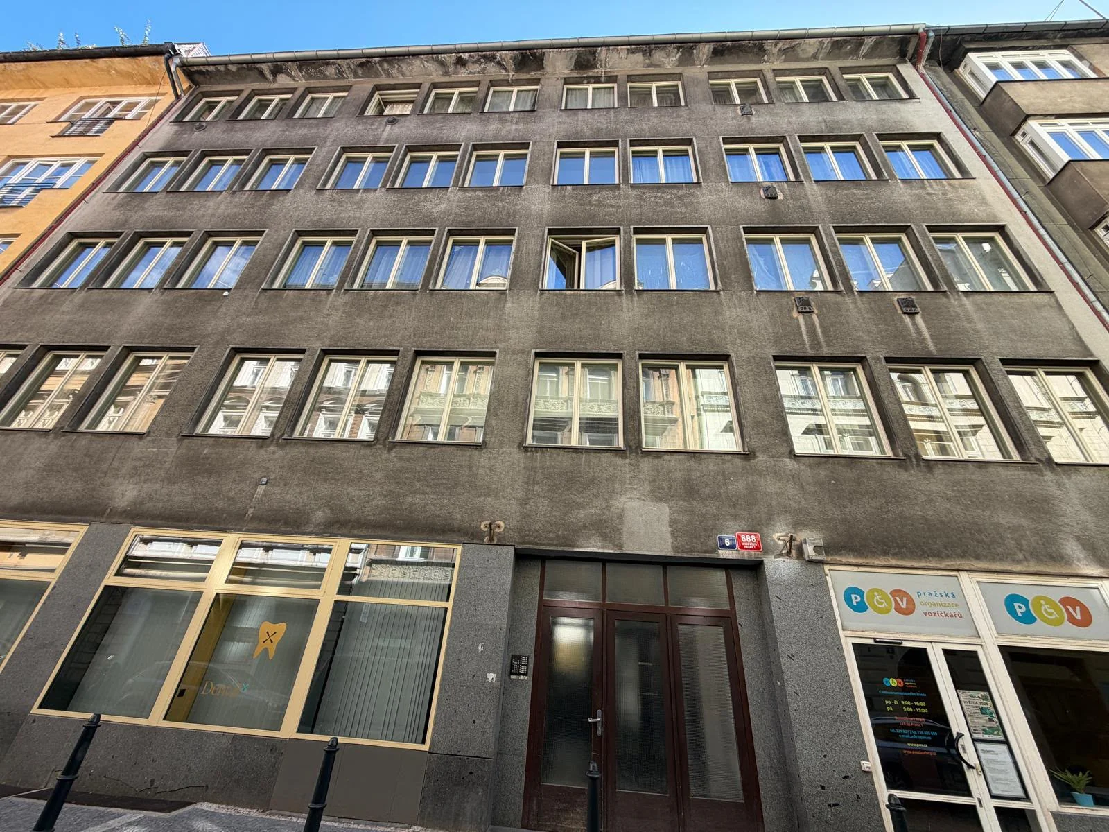 Pohled vzhůru na řady špaletových oken nad vstupem domu Benediktská 688/6 v Praze 1.