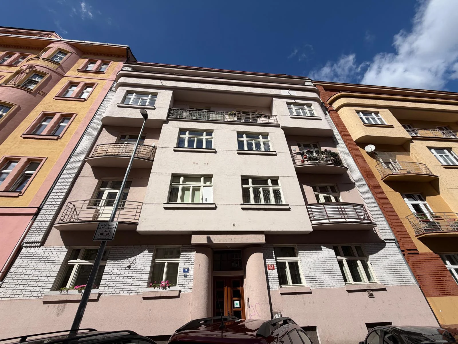 Uliční průčelí domu Kyjevská 779/9 v Praze 6 se světlými špaletovými okny a zaoblenými balkony.