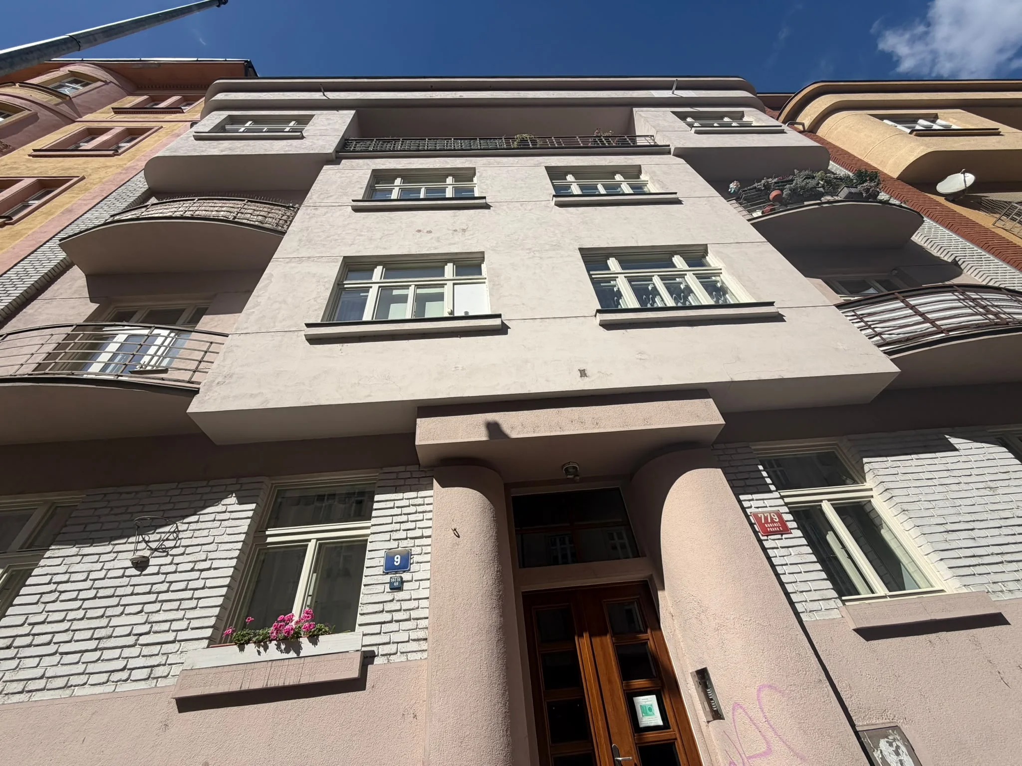 Bližší pohled na vstup se sloupy a okna ve vyšších patrech domu Kyjevská 779/9 v Praze 6.