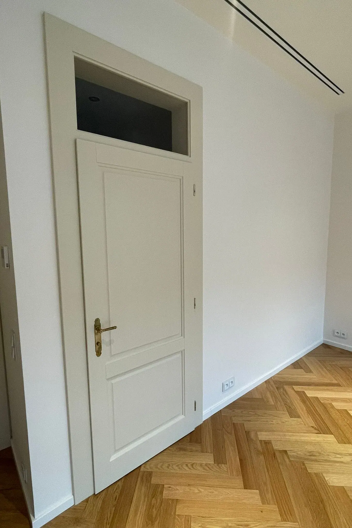 Bílé interiérové dveře s mosaznou klikou a horním sklem