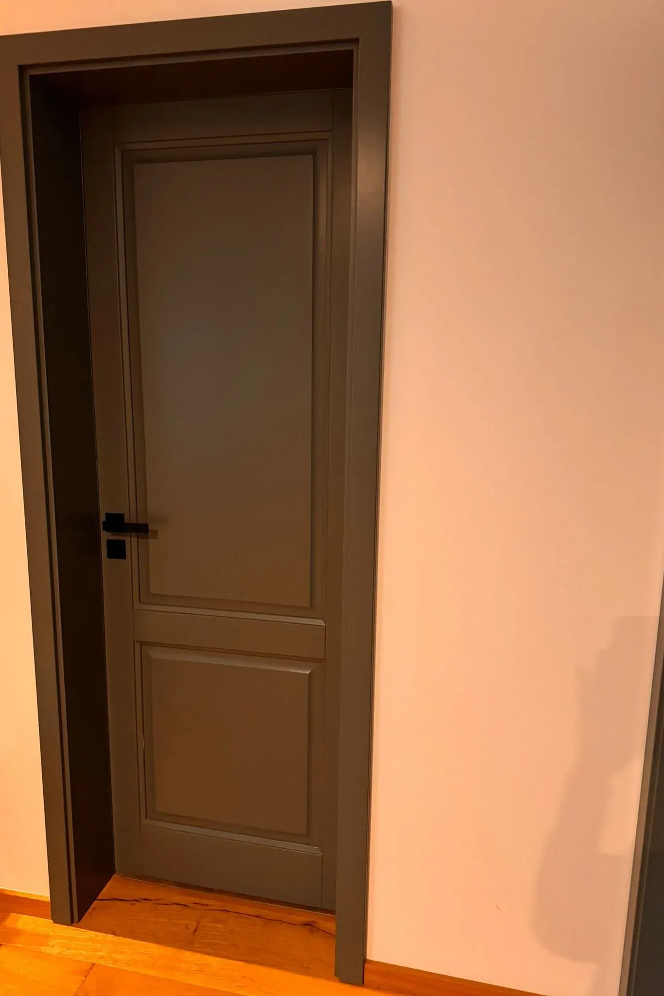 Šedé interiérové dřevěné dveře s černým madlem